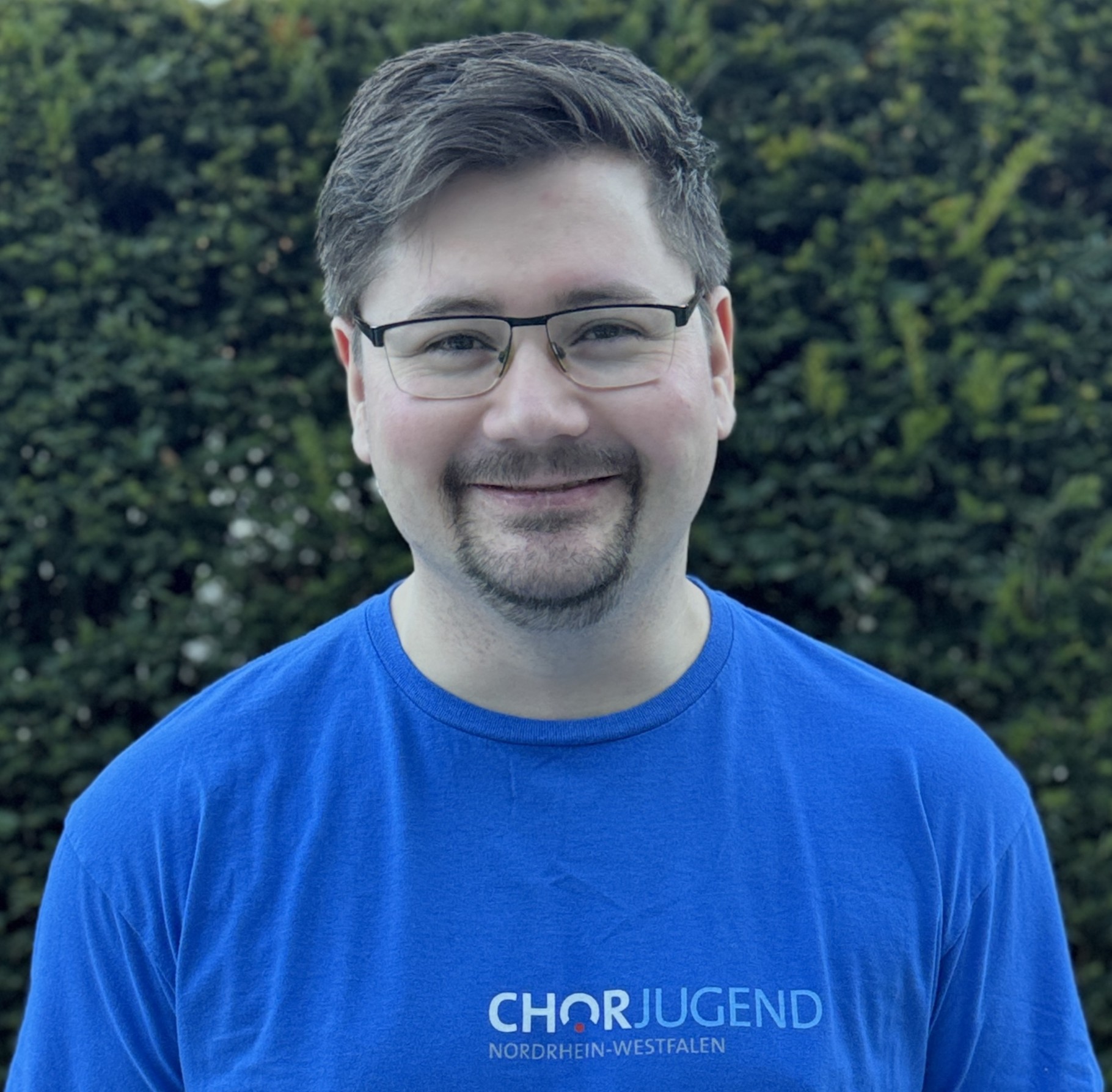 Person mit kurzen braunen Haaren und Brille