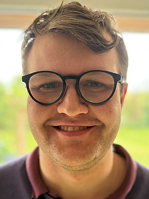 Person mit kurzen Haaren und schwarzer Brille