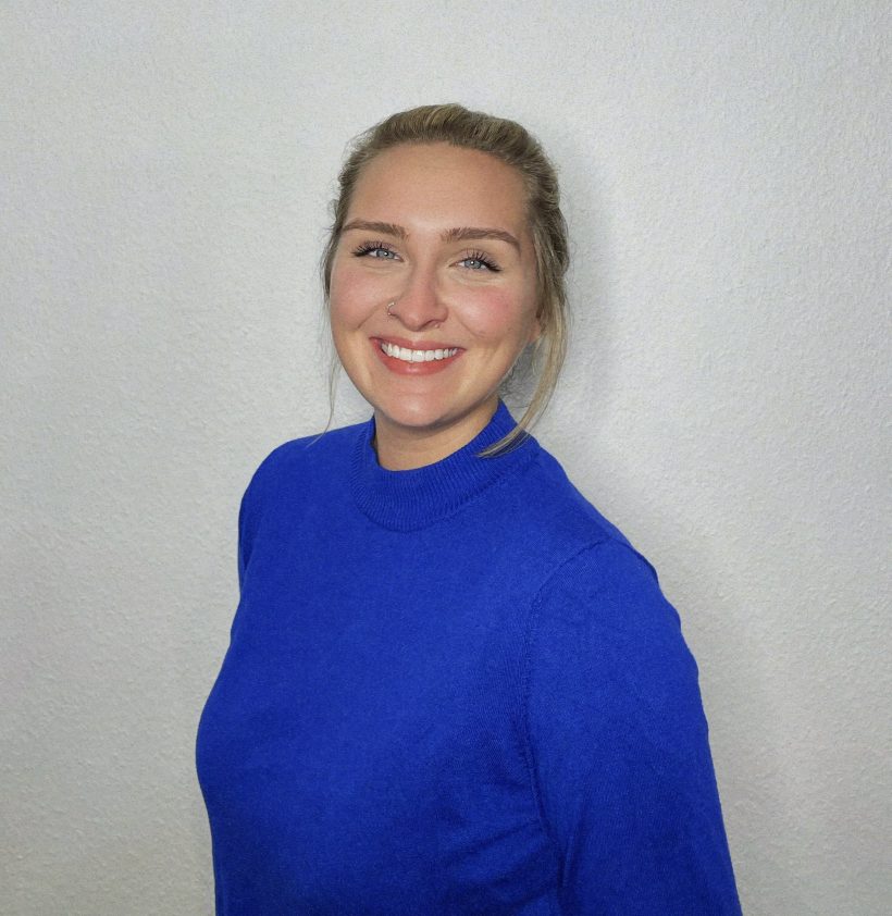 Porträt junge Frau, helle Haare, lächelnd, blauer Pullover