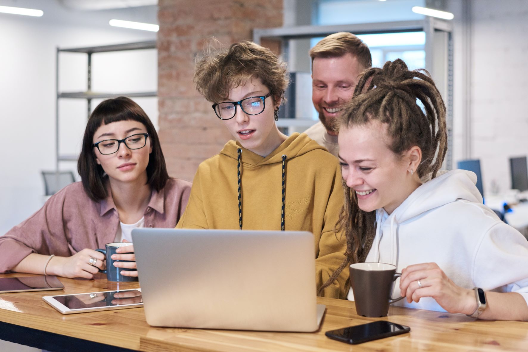 Vier junge Menschen sitzen um Laptop herum