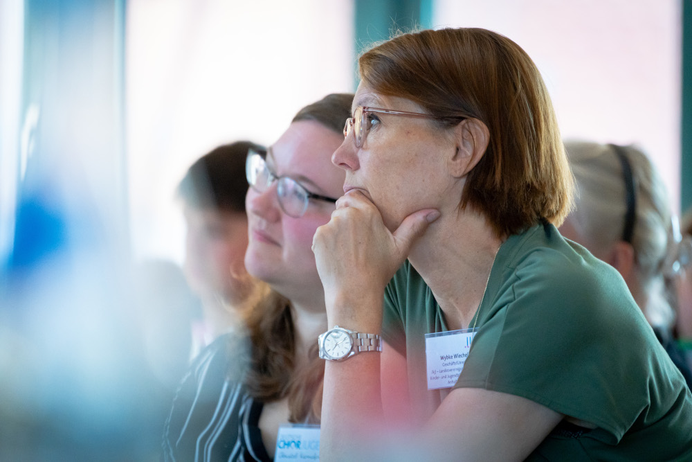 Zwei zuhörende Personen von der Seite fotografiert.