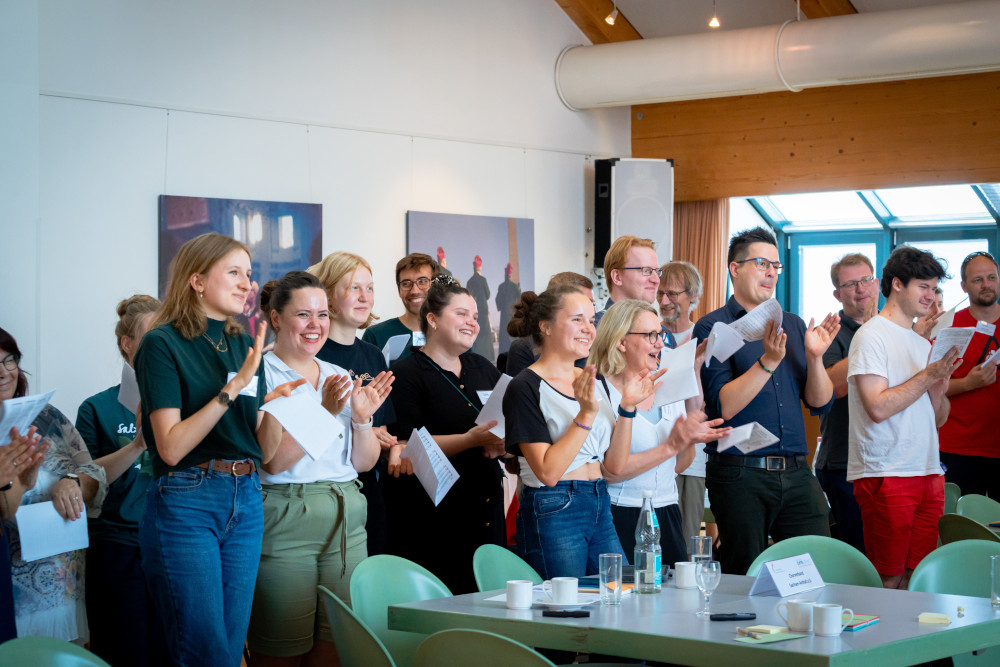 Junge Menschen, die in Reihen stehen, in die Hände klatschen und fröhlich aussehen.