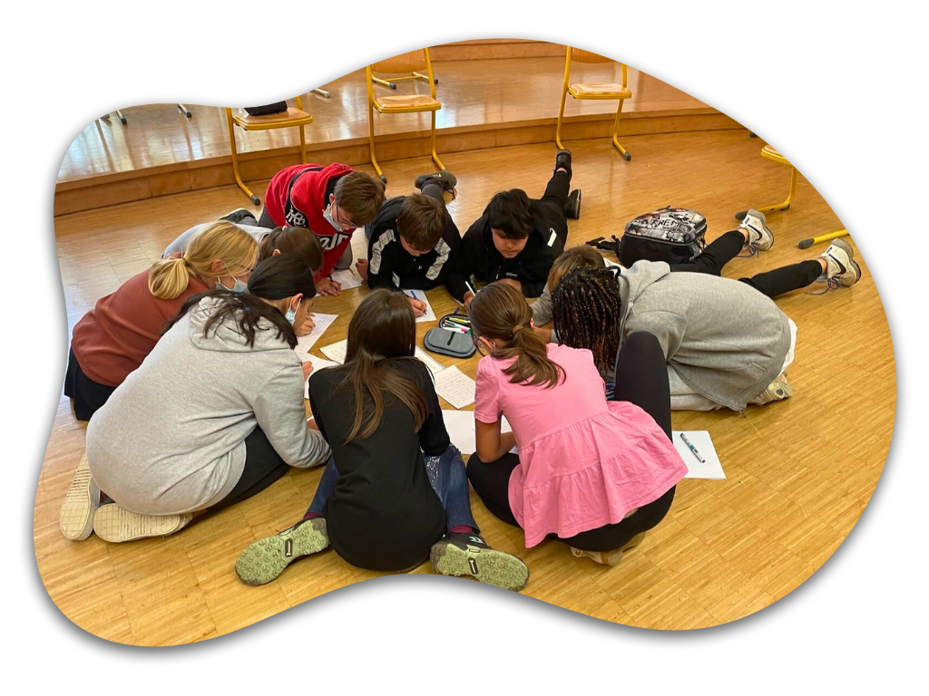 Gruppe von Kindern, die im Kreis auf dem Boden sitzt und schreibt. Bild: Jacinta Pereira