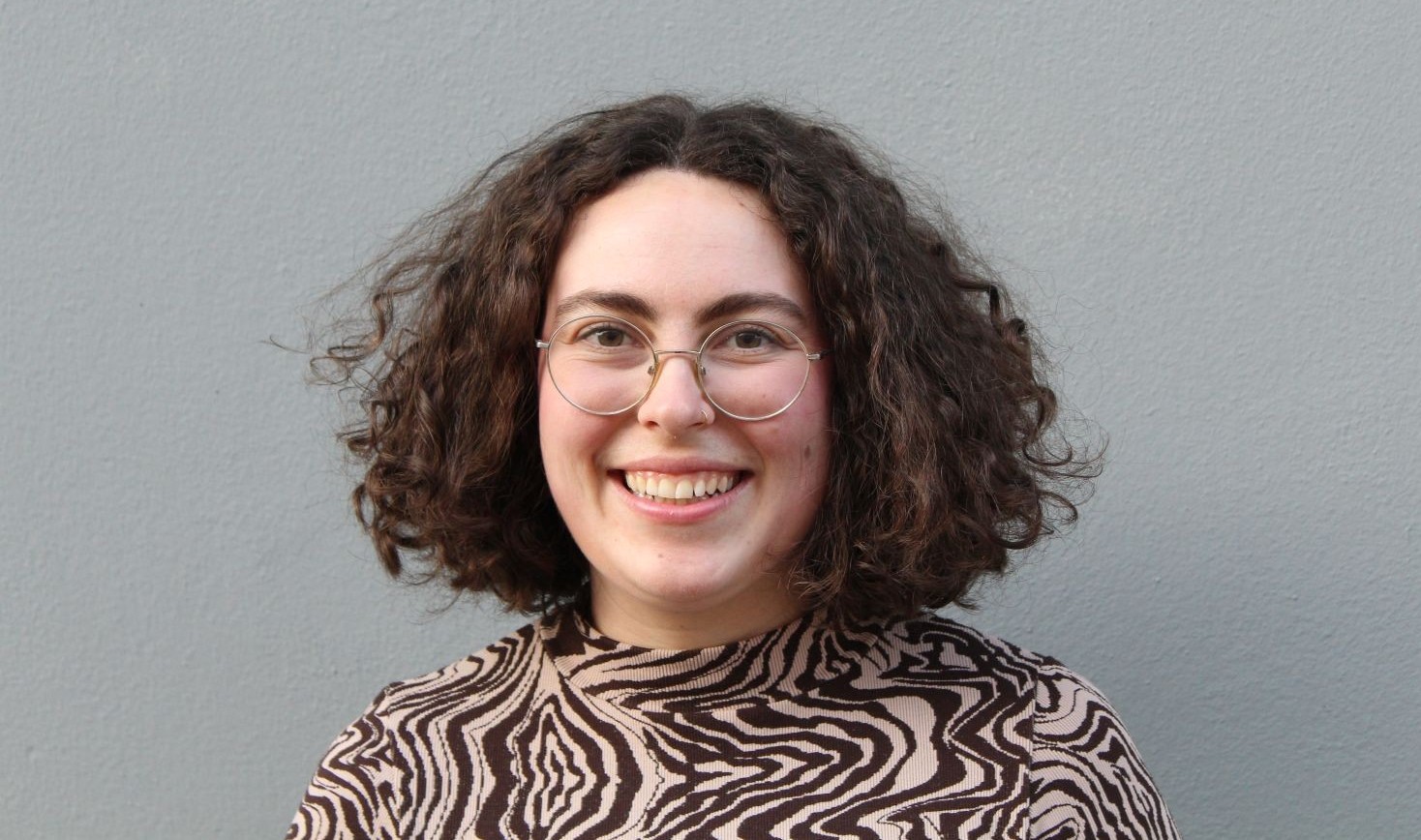 Person mit dunklen Locken und Brille