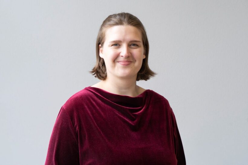 Portrait von Person mit braunen mittellangen Haaren und rotem Pullover