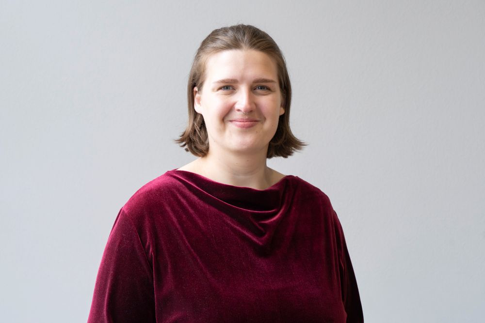 Portrait von Person mit braunen mittellangen Haaren und rotem Pullover