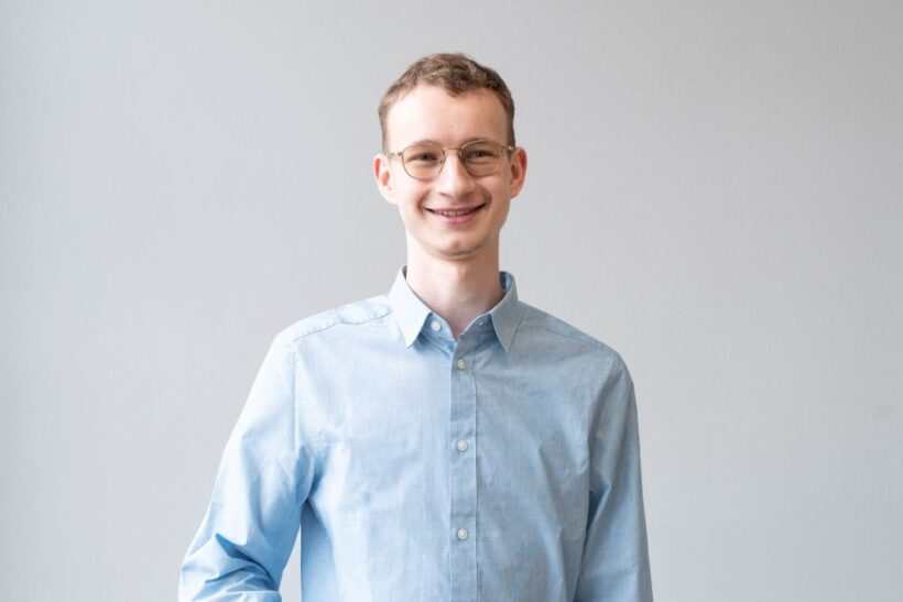 Portrait von Person mit kurzen Haaren, Brille und hellblauem Hemd